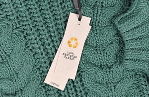 Image of green knitted garment with 100% recycled tag